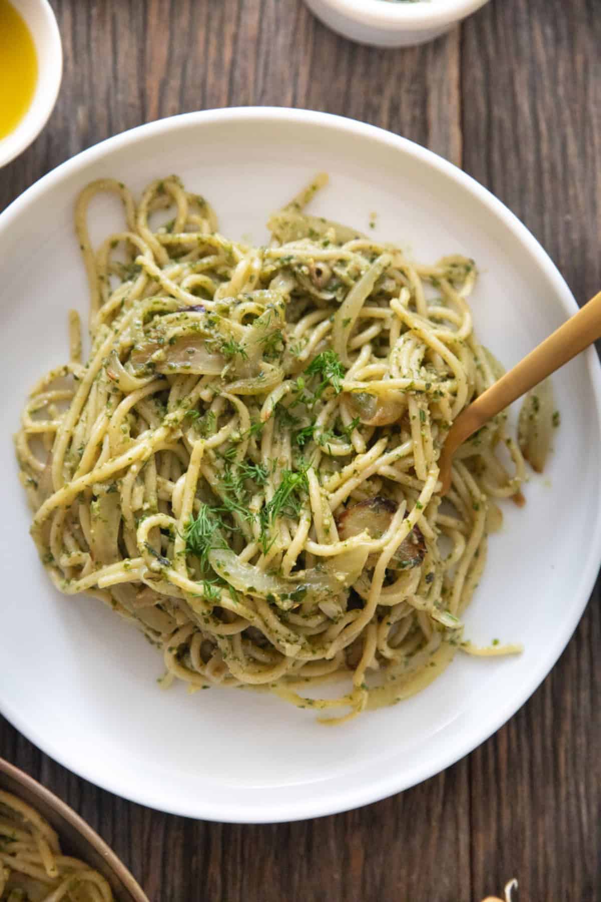 Creamy pesto pasta on a white plate.