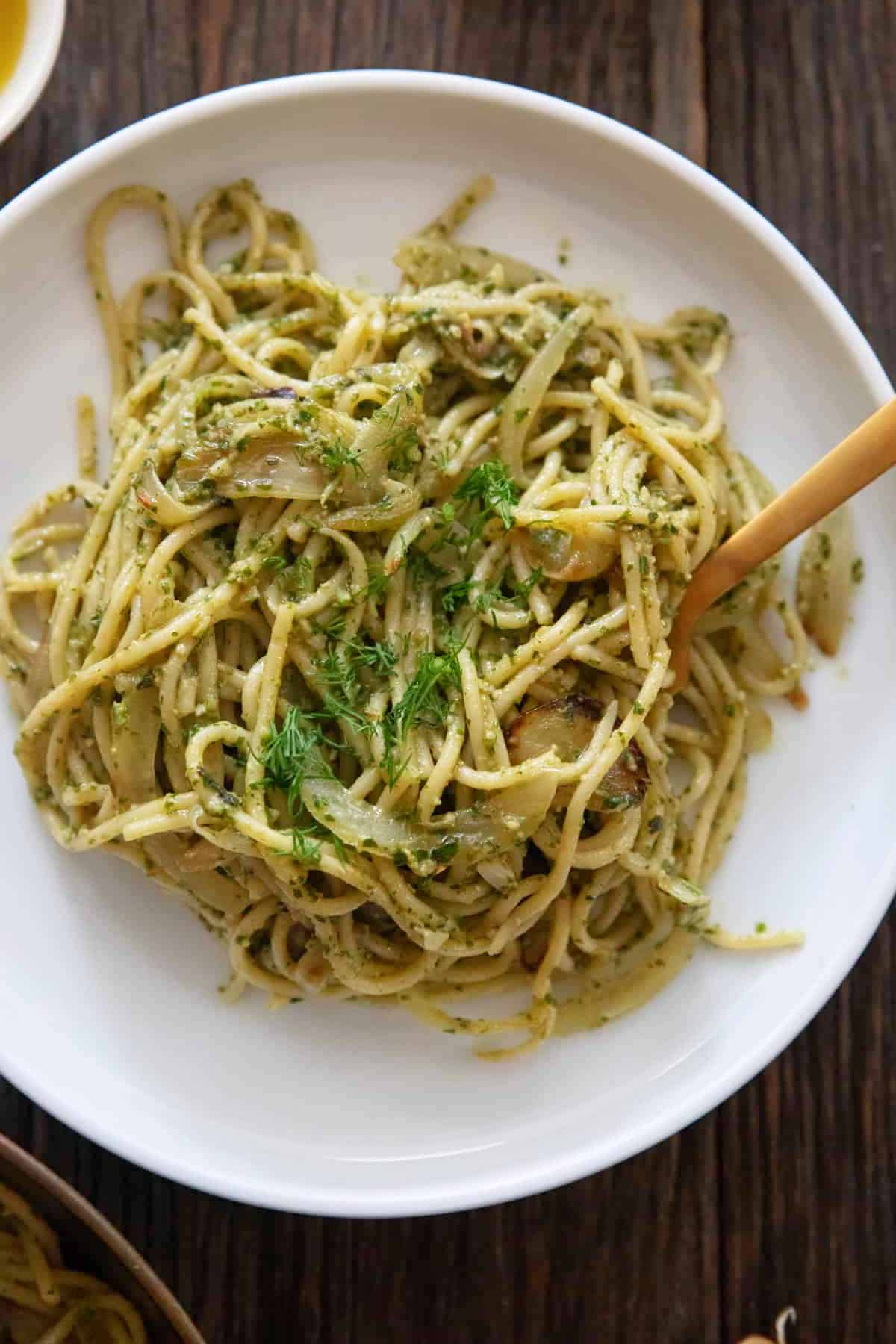 Creamy pesto pasta on a white plate.