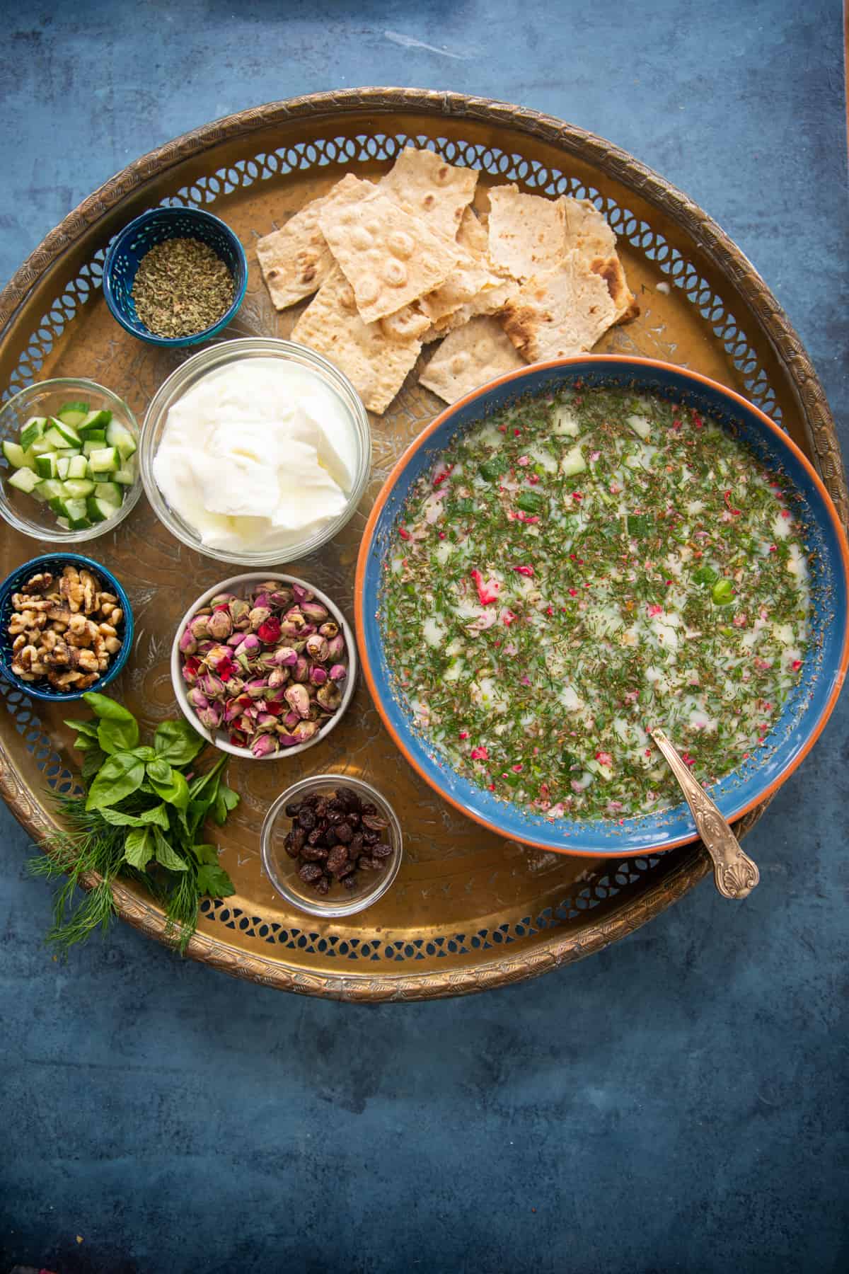 A large bowl of abdoogh khiar on a golden tray with other ingredients. 