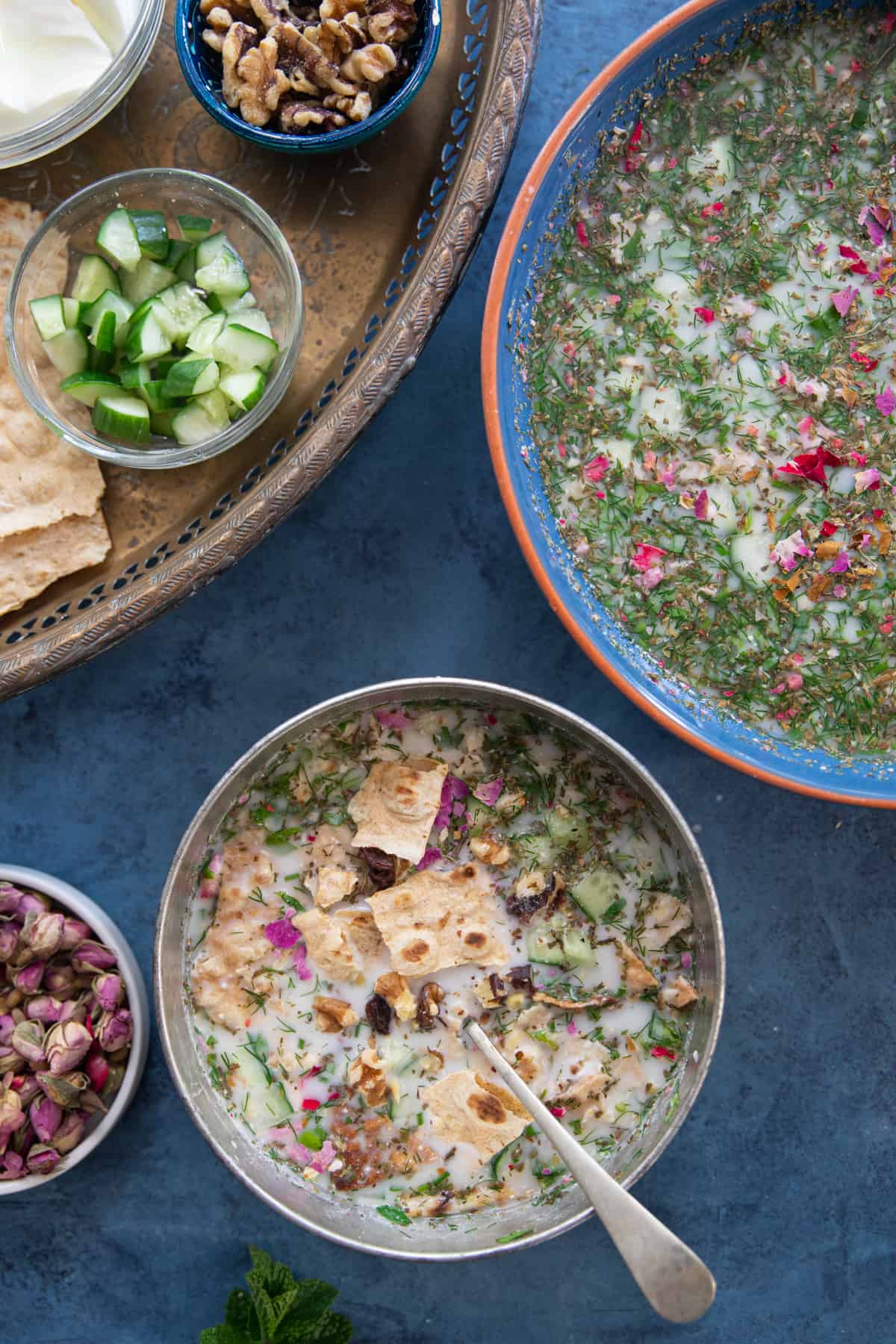 A bowl of Persian cold yogurt soup on a blue backdrop. 