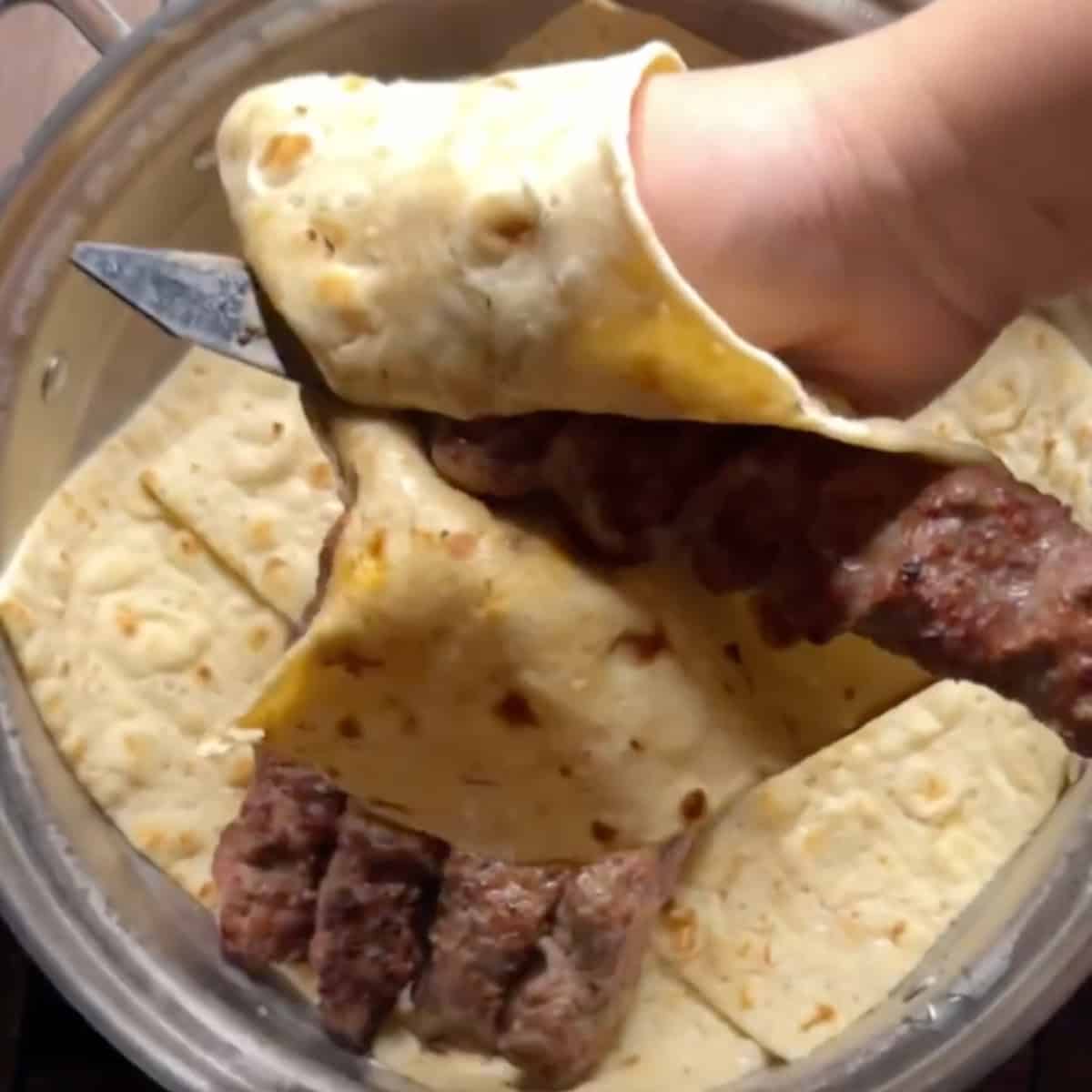 Using a piece of lavash, loosen both ends of the kabab from the skewer and slide it into the pot. Cover the pot with the lid to keep the kabobs warm while you continue grilling the rest.