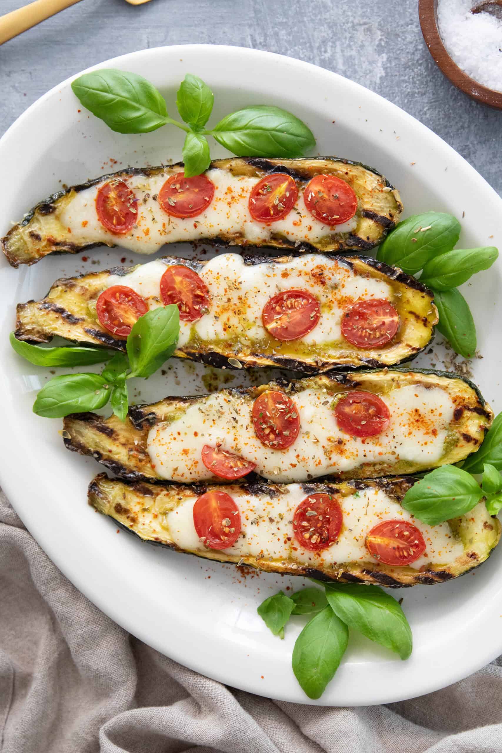 Grilled caprese style stuffed zucchini boats in a platter. 