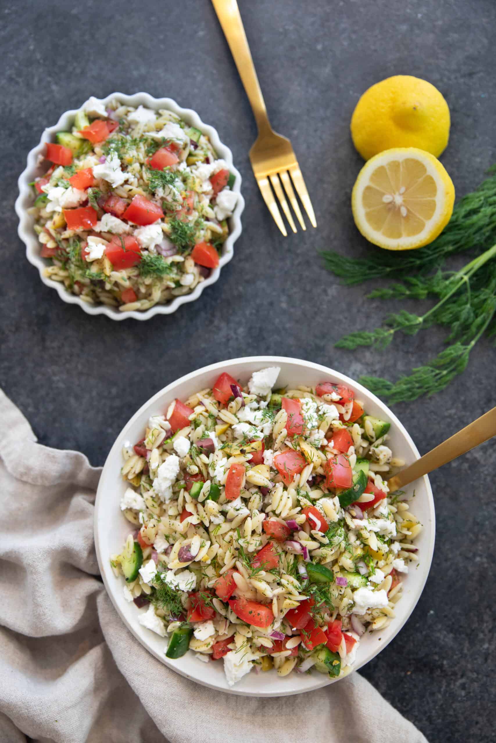 Overhead shot of Mediterranean orzo salad on a black backdrop.