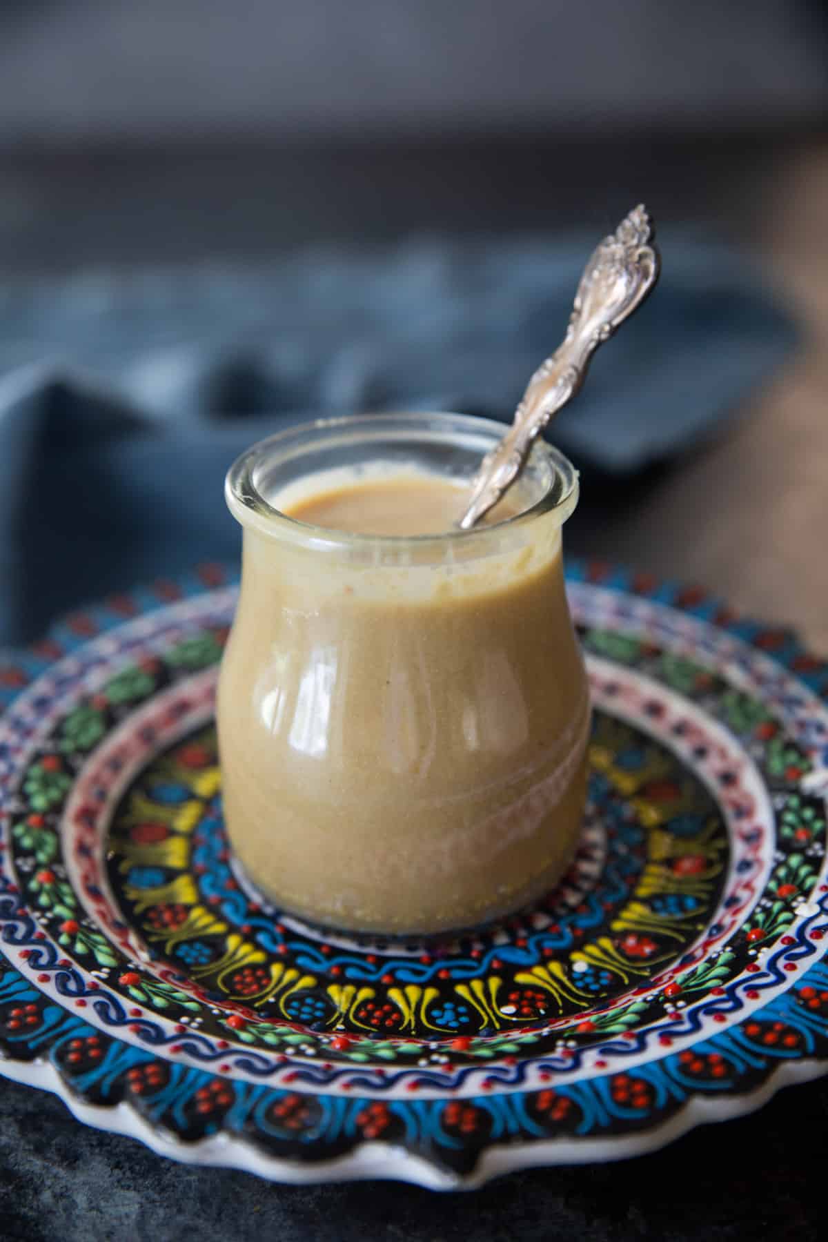 A jar of tahini on a colorful plate. 