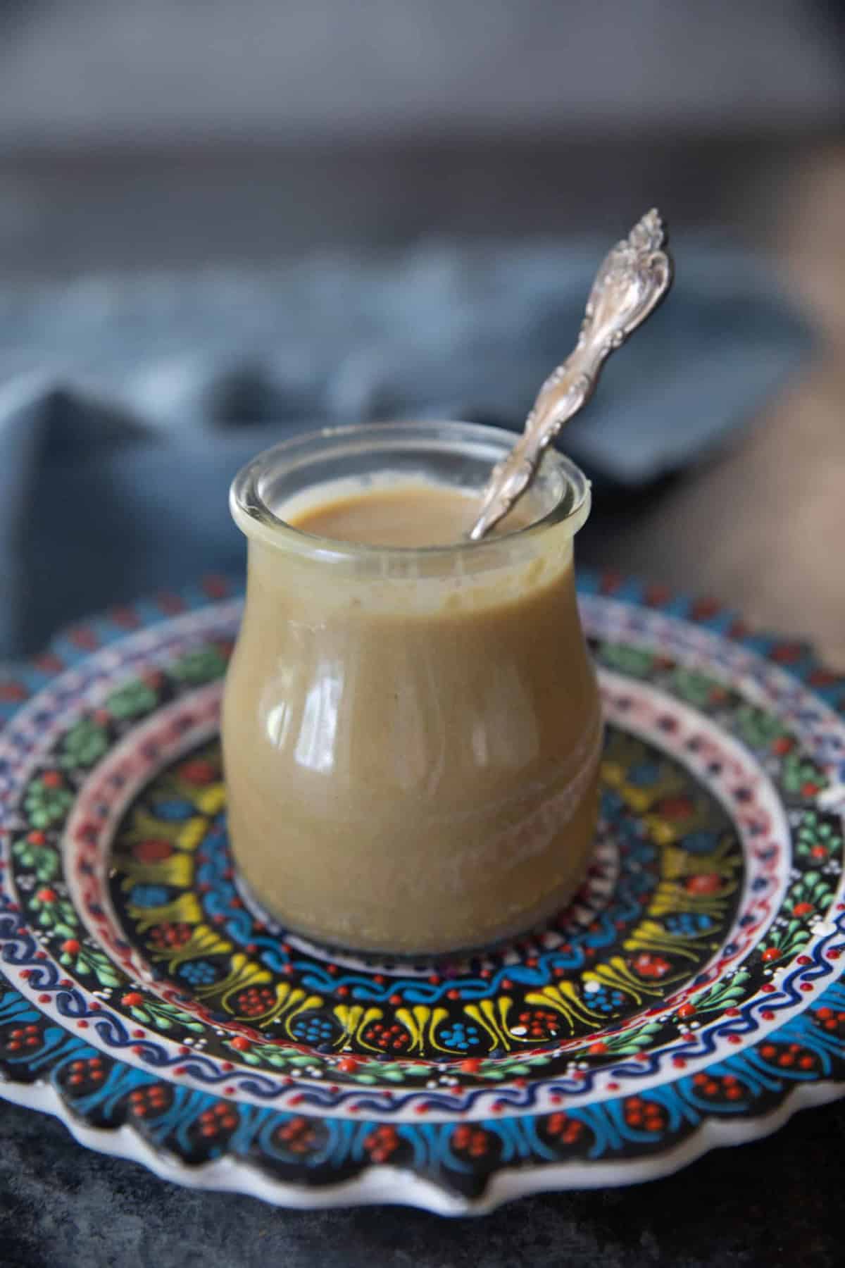 A jar of tahini on a colorful plate.