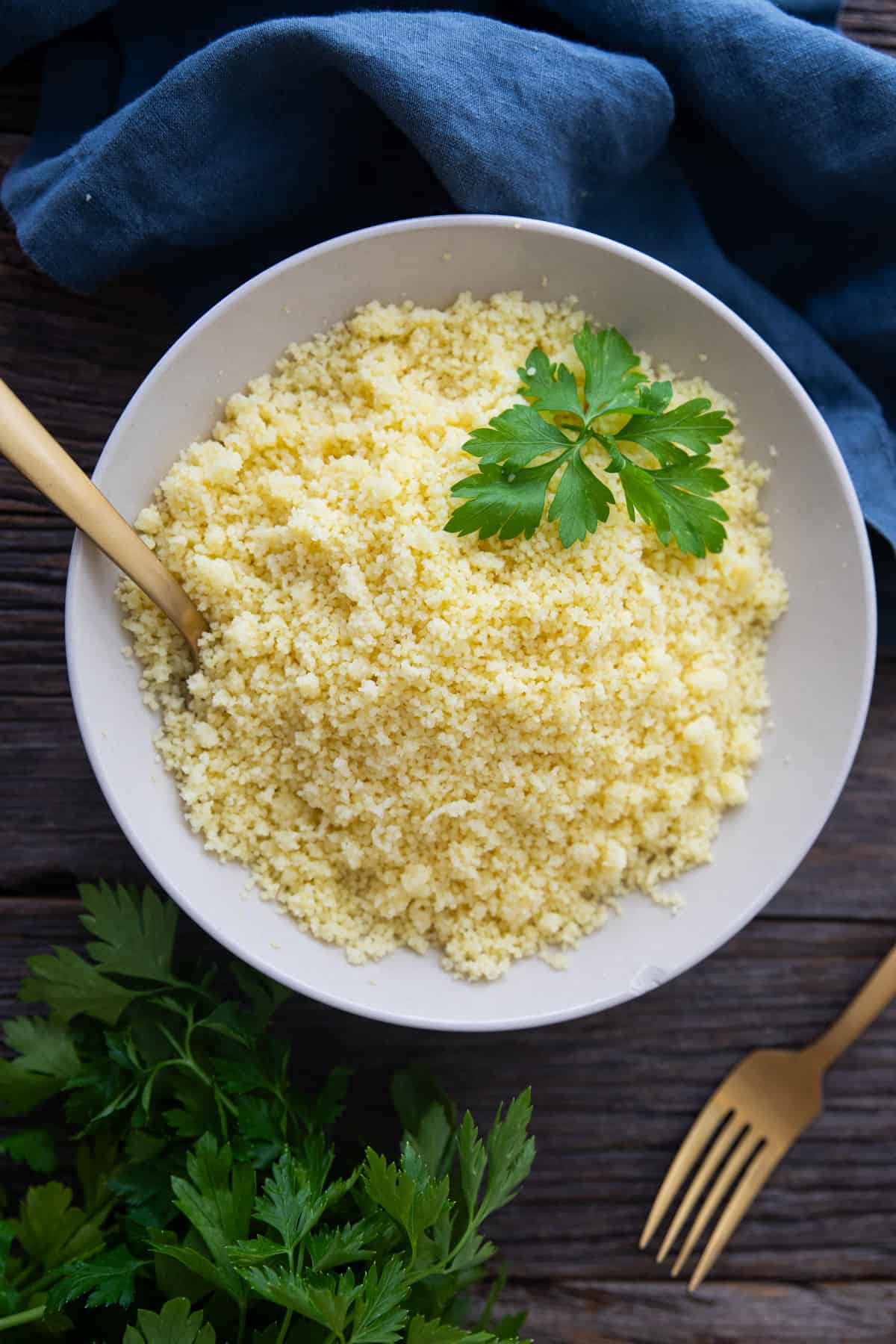 Overhead shot of couscous in a bowl topped with parsley. 