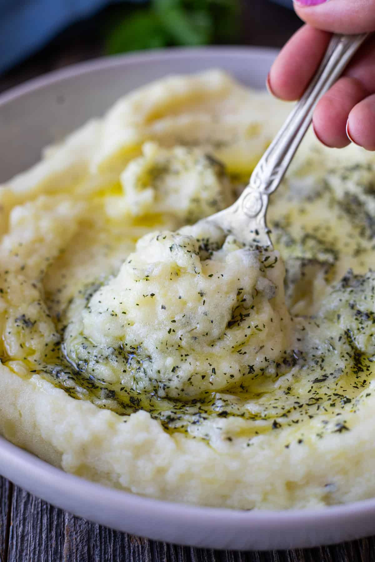 A spoon picking some mashed potatoes from a bowl. 