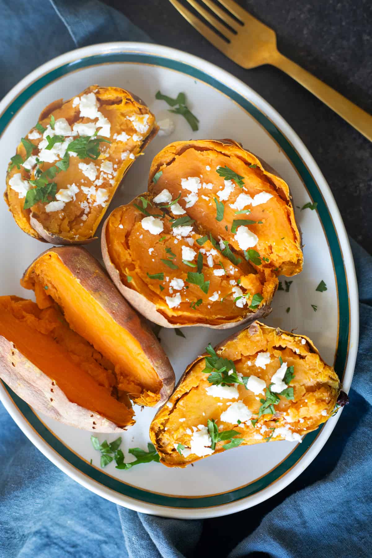 Overhead shot of baked sweet potato topped with feta and herbs. 