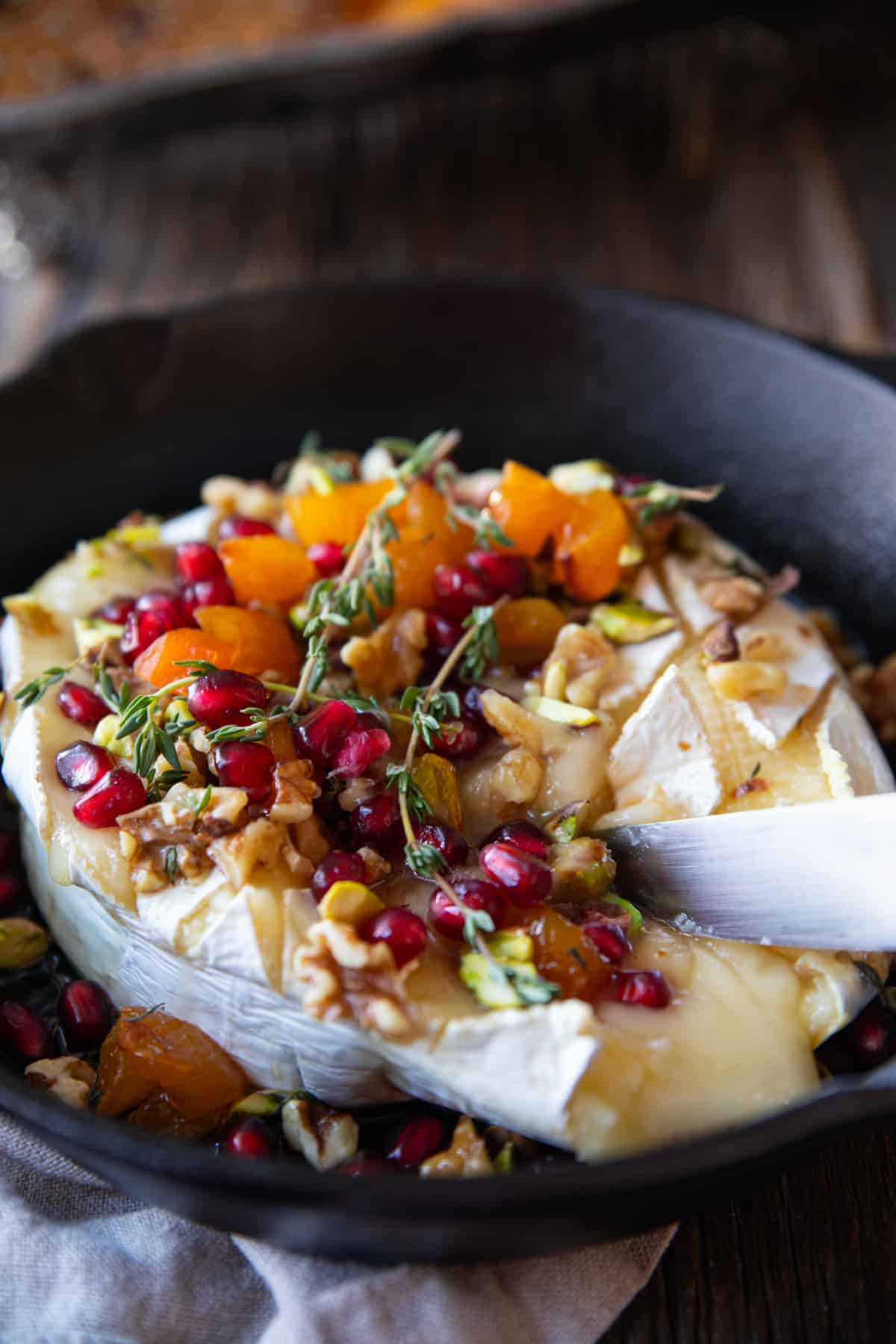 baked brie in a cast iron skillet topped with dried fruit and nuts. 