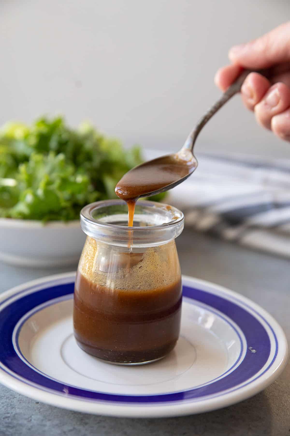 A spoon pouring balsamic dressing into a jar. 