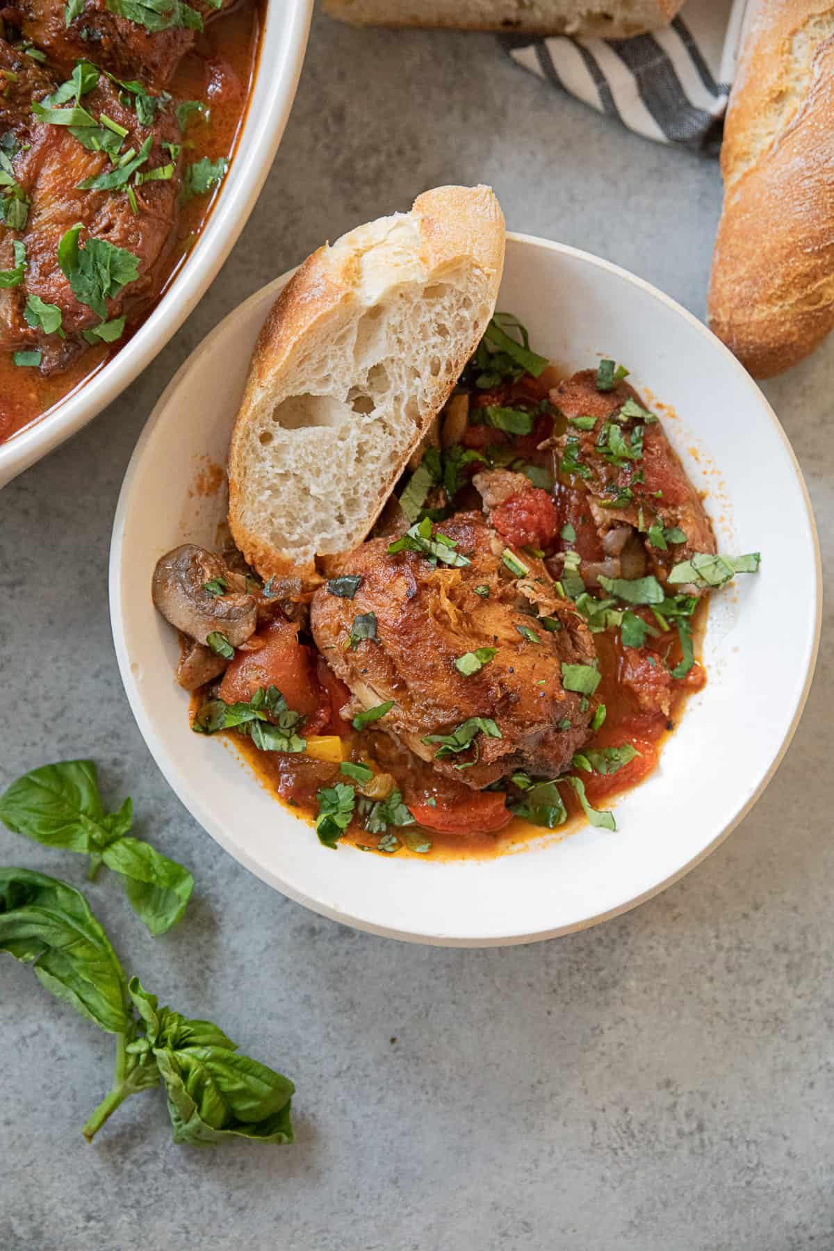 A bowl of Italian chicken cacciatore with bread. 