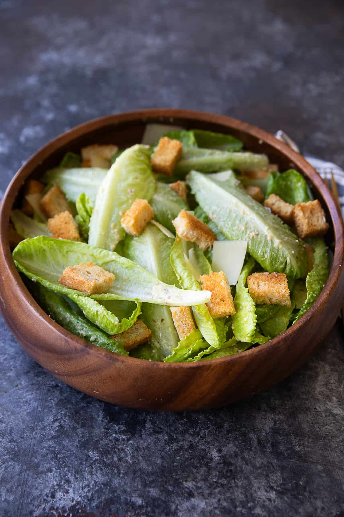 wooden brown bowl filled with delicious homemade Caesar Salad and croutons