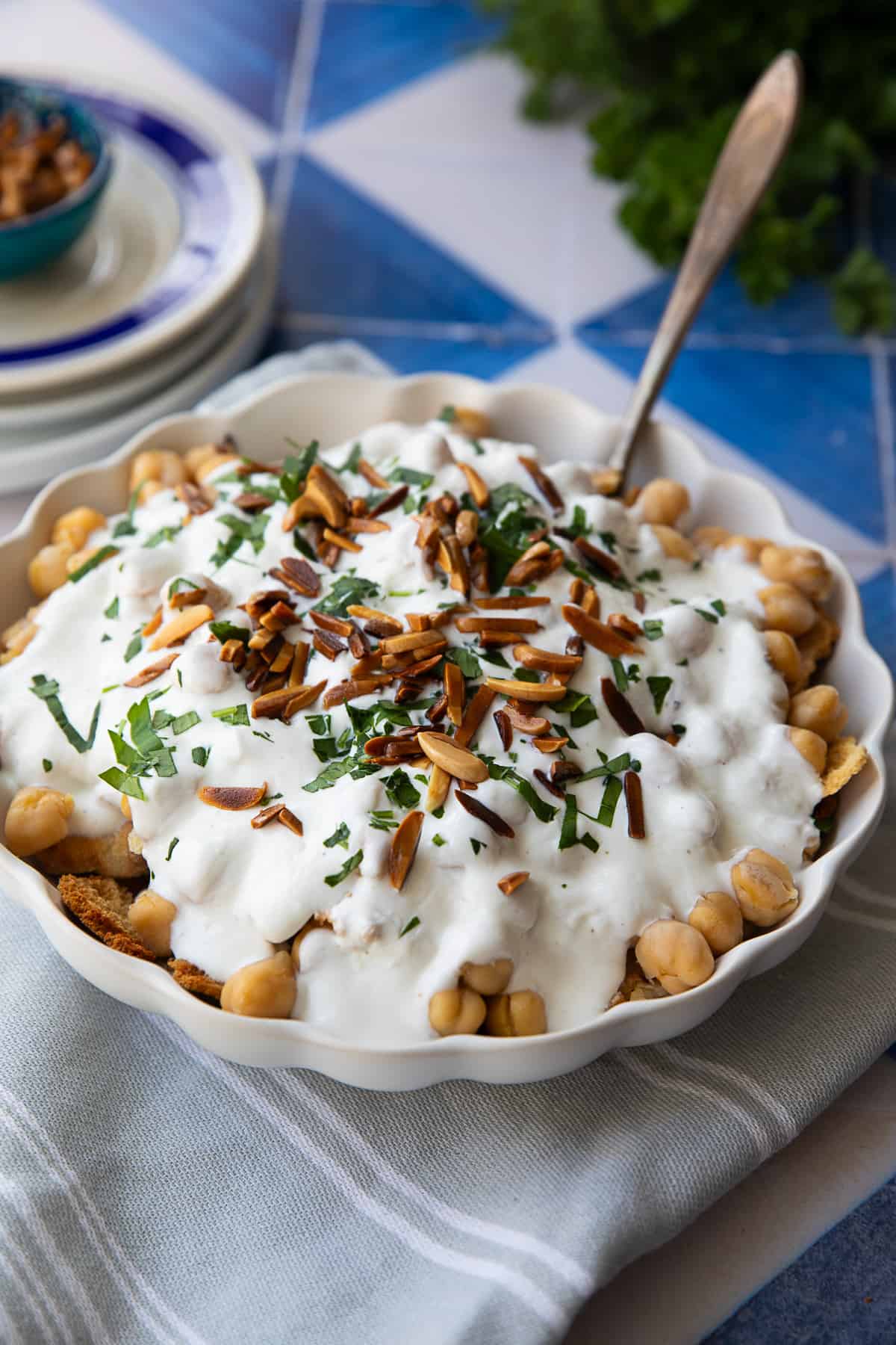 Fatteh dish made with layers of toasted pita, creamy yogurt, flavorful chickpeas, and garnished with slithered almonds are parsley