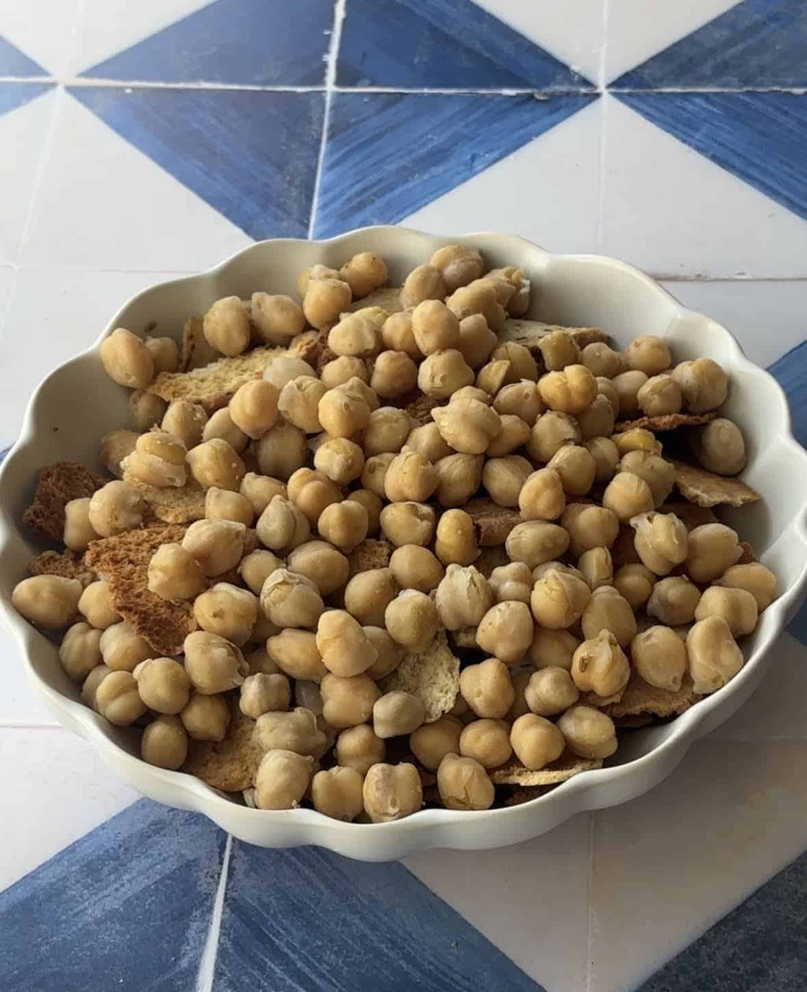 a white dish layered with toasted pita bread and spiced chickpeas 