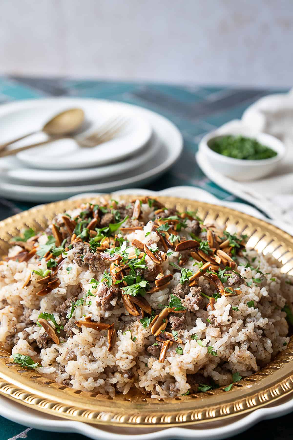 A close-up image of a plate filled with Hashweh rice, garnished with toasted pine nuts and fresh parsley.