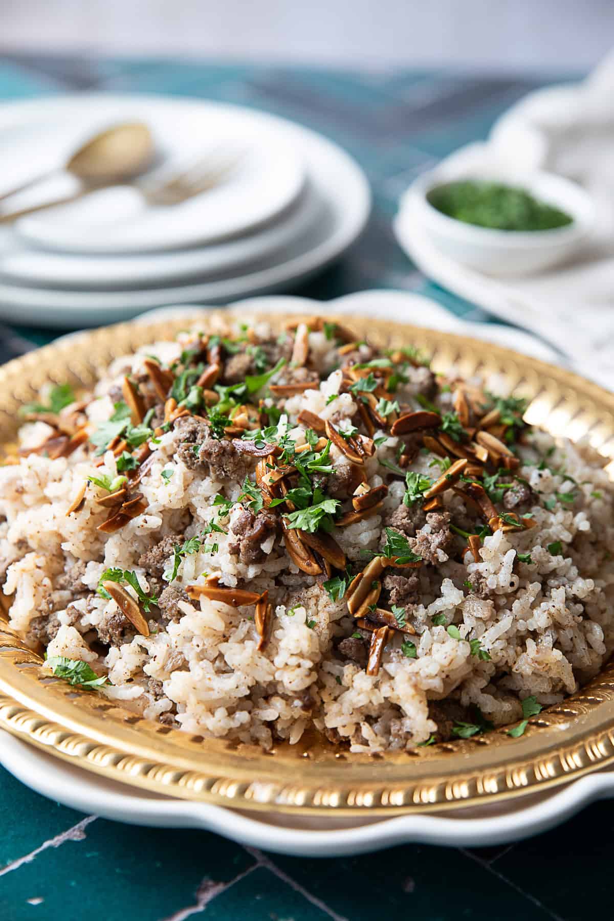 A plate of Hashweh rice, a traditional Middle Eastern dish made with seasoned ground beef, rice, and warm spices, topped with toasted pine nuts and chopped parsley.