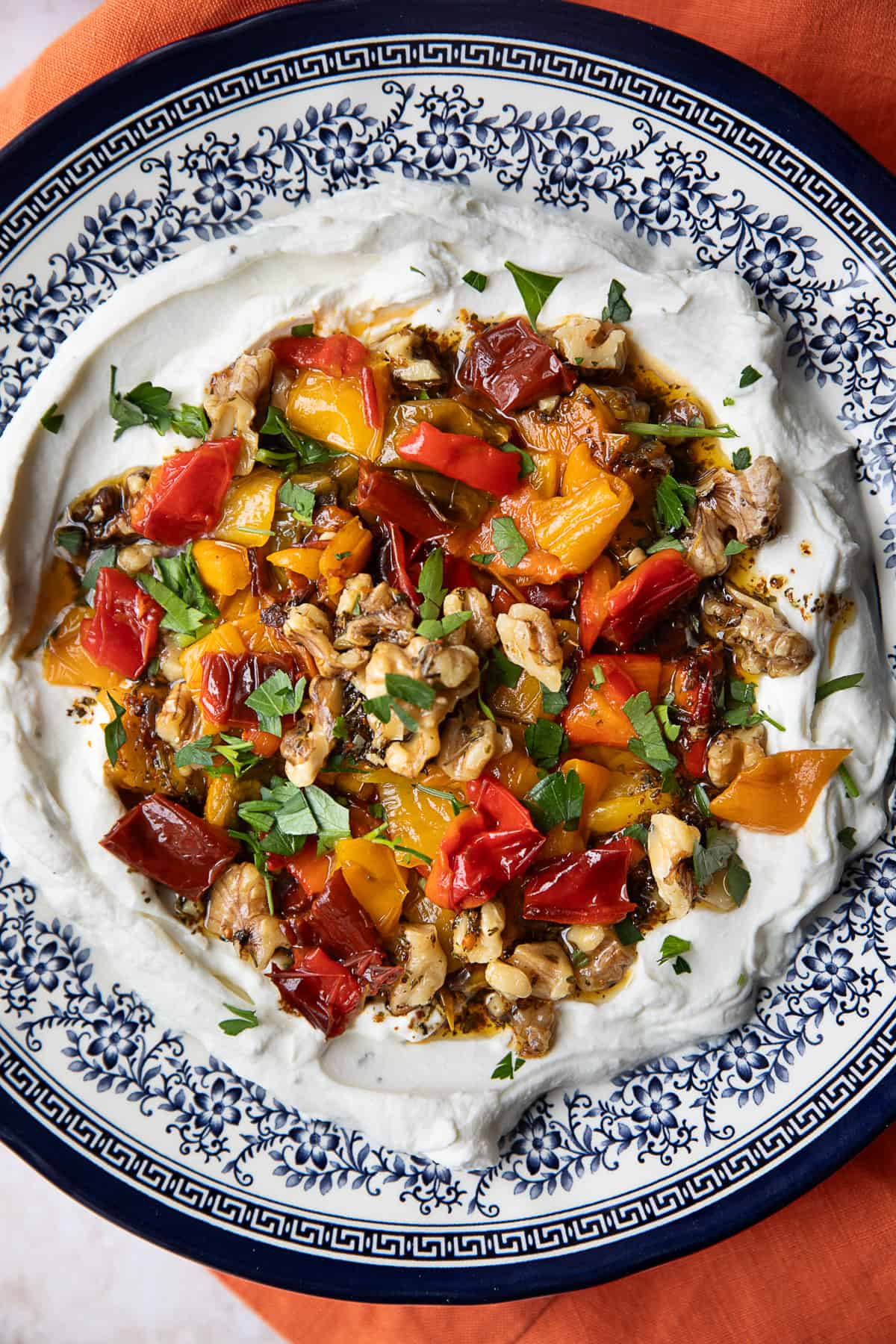 Labneh dip topped with roasted peppers in a floral blue bowl.