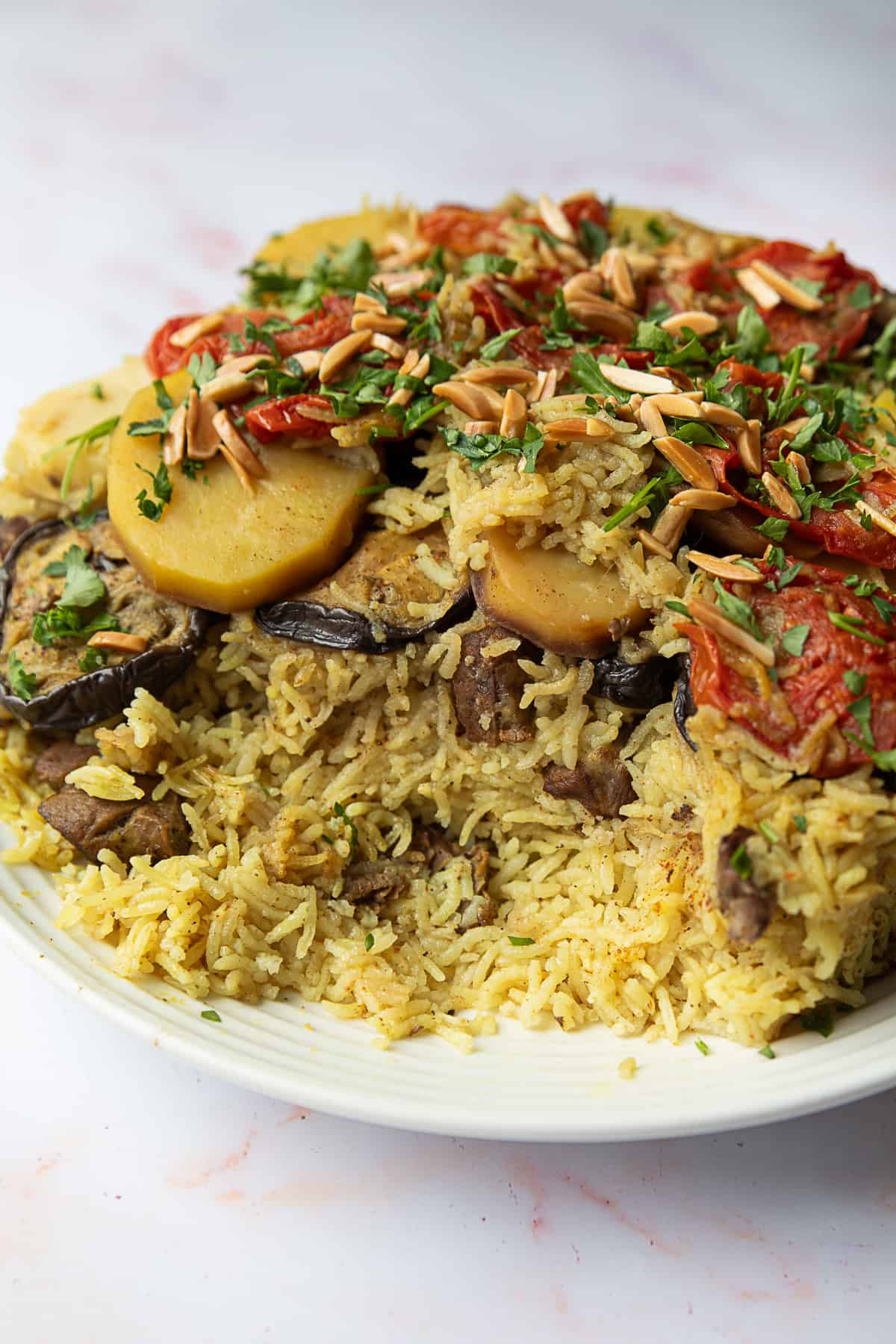 Traditional maqluba, featuring layers of flavorful meat, aromatic rice, and vibrant vegetables, perfectly complemented by fresh parsley and toasted slivered almonds.