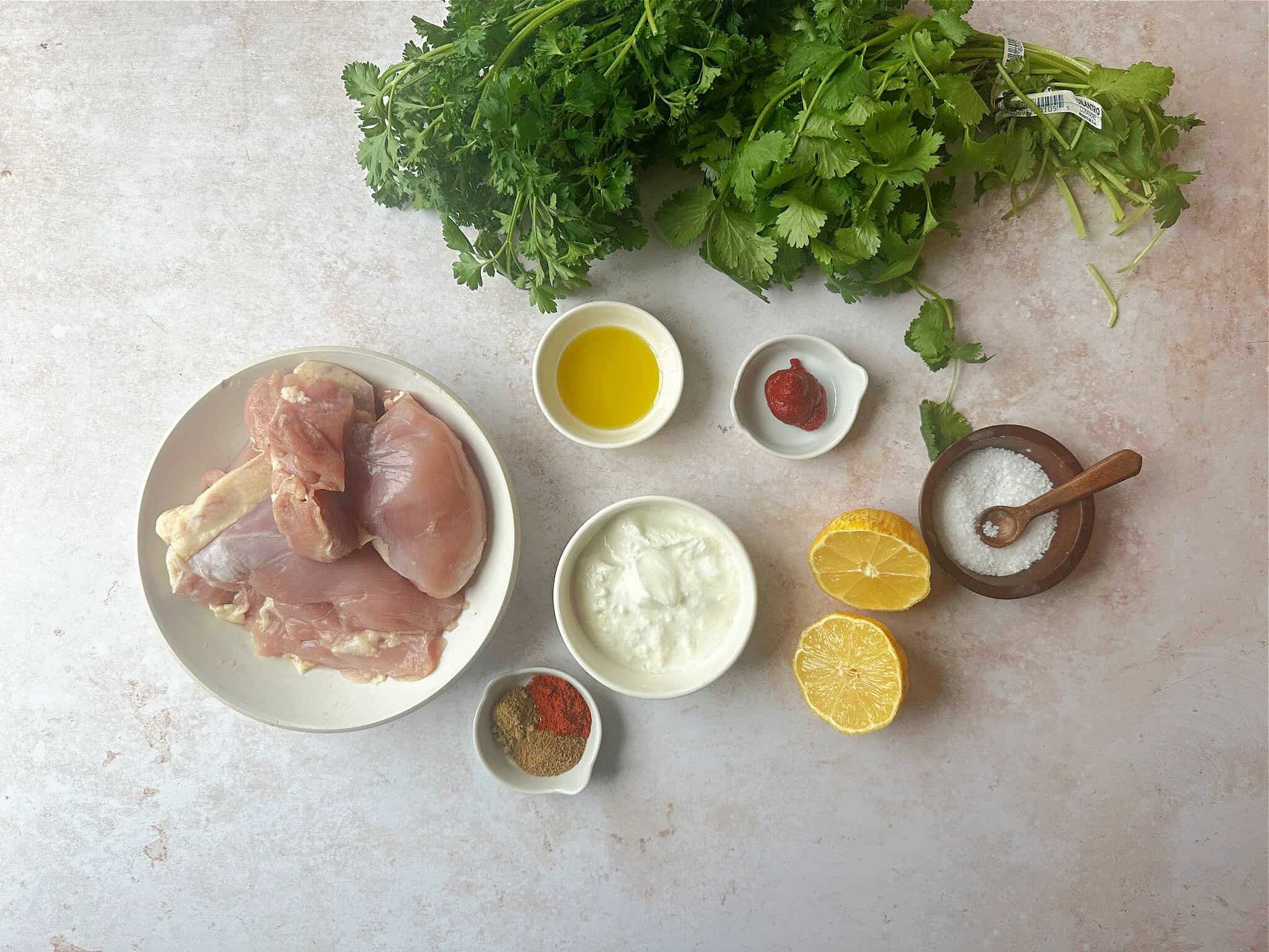  Ingredients for Mediterranean chicken skewers: chicken thighs, olive oil, yogurt, lemon juice, tomato paste, parsley, cilantro, cumin, coriander, paprika, salt, and pepper.