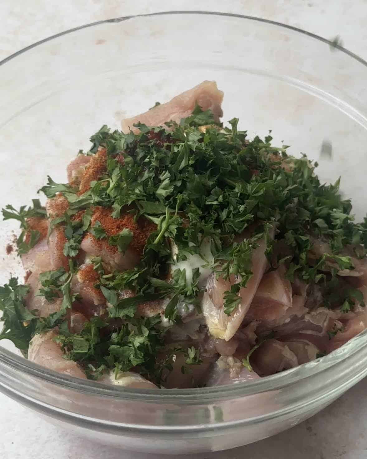 Cubes of chicken topped with a marinade made of olive oil, yogurt, lemon juice, tomato paste, parsley, cilantro, cumin, coriander, paprika, salt, and pepper.





