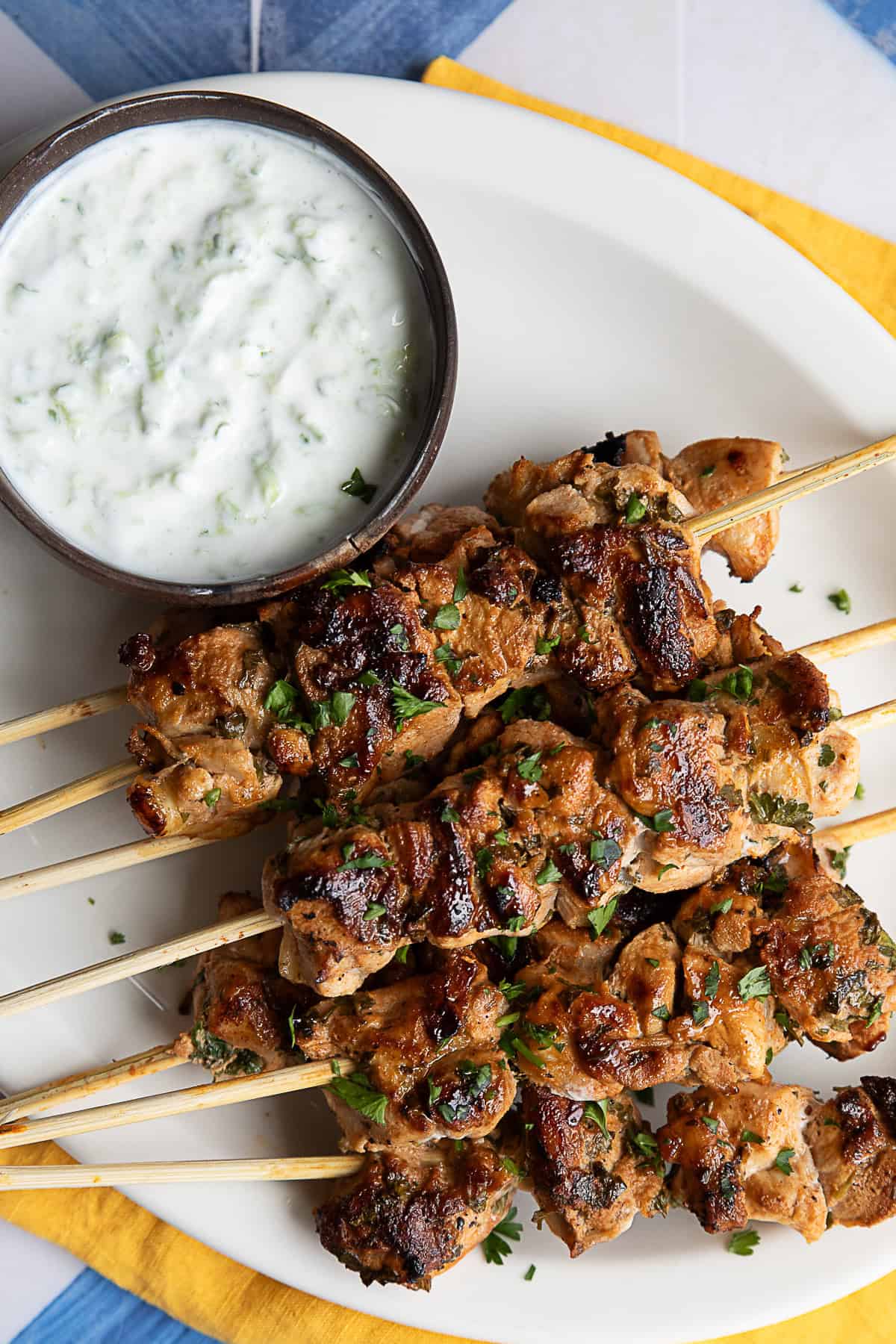 Golden-brown grilled Mediterranean chicken skewers arranged on a white plate, garnished with fresh herbs 