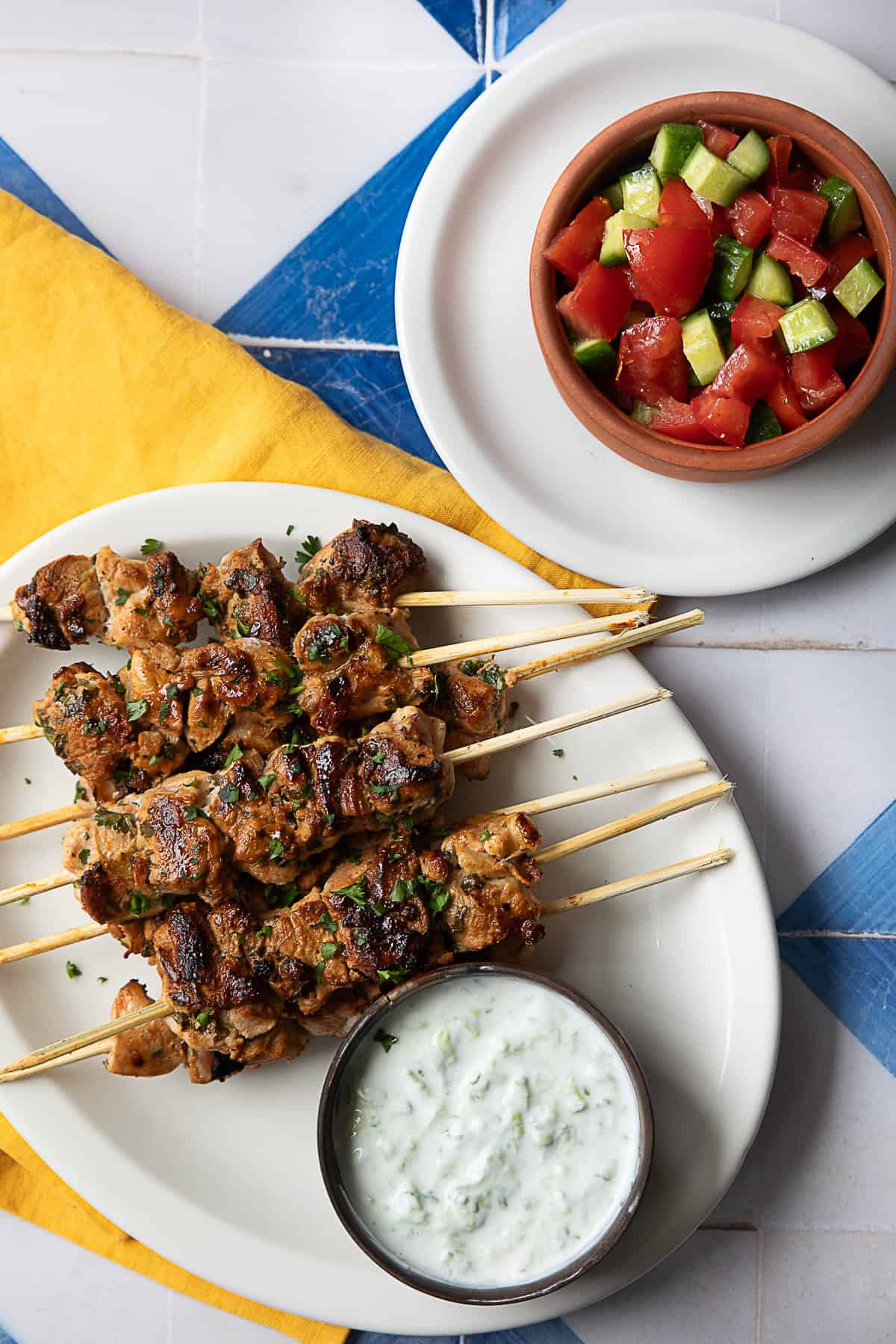 Mediterranean chicken skewers served with tzatziki sauce and cucumber and tomato salad.