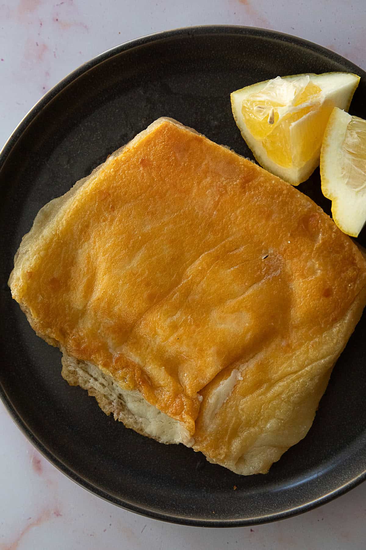 A golden brown saganaki with lemon slices on the side.