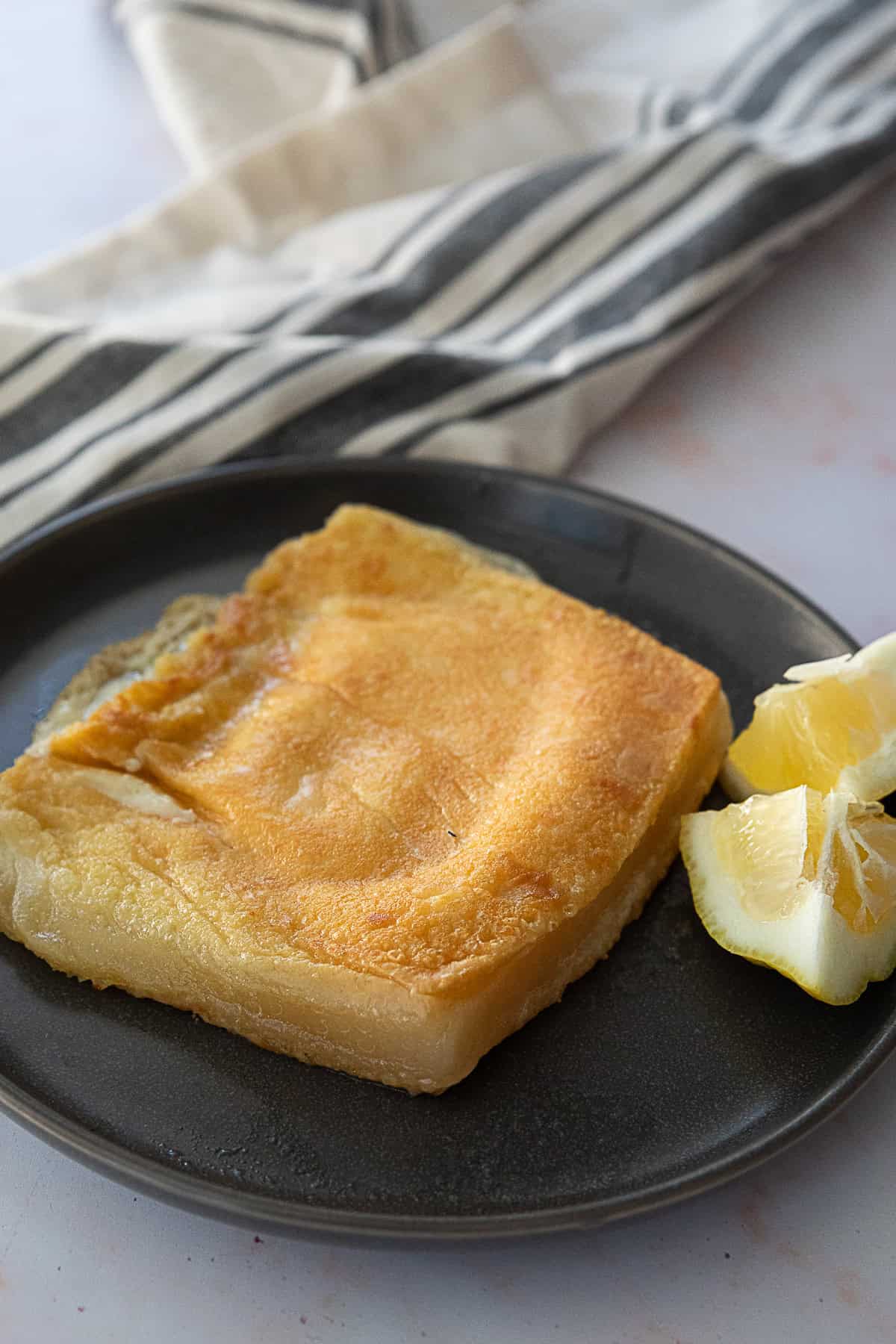 Saganaki fried cheese with some lemon slices on the side.