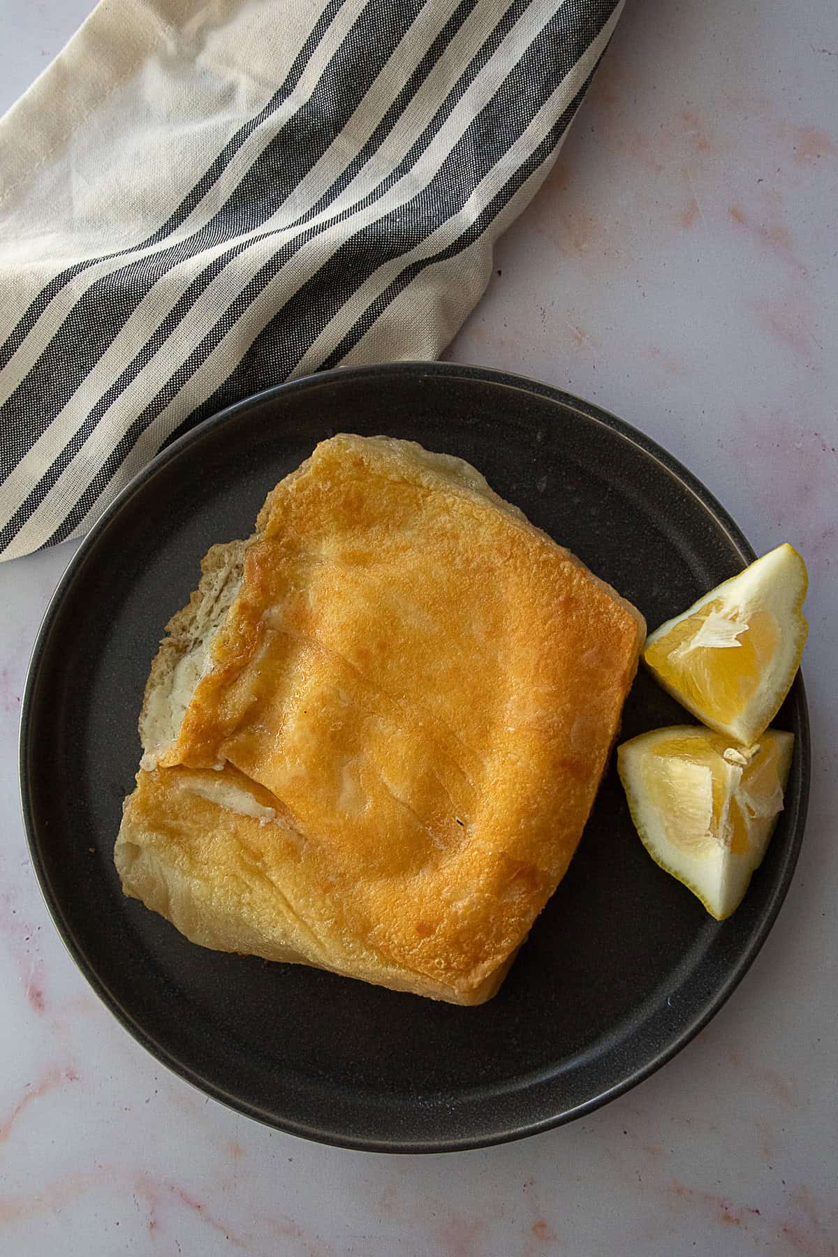 A plate that has golden brown fried cheese saganaki, with lemon on the side.