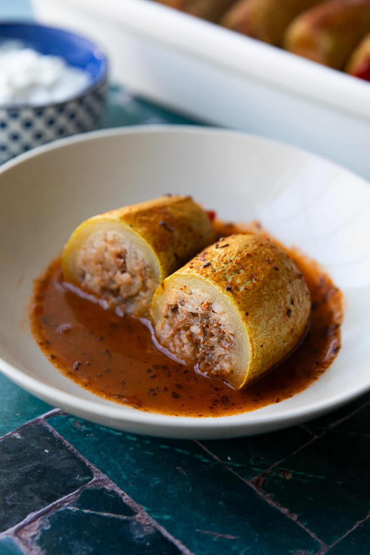 Easy Kabak Dolmasi Turkish stuffed zucchini sliced in half and served in sauce