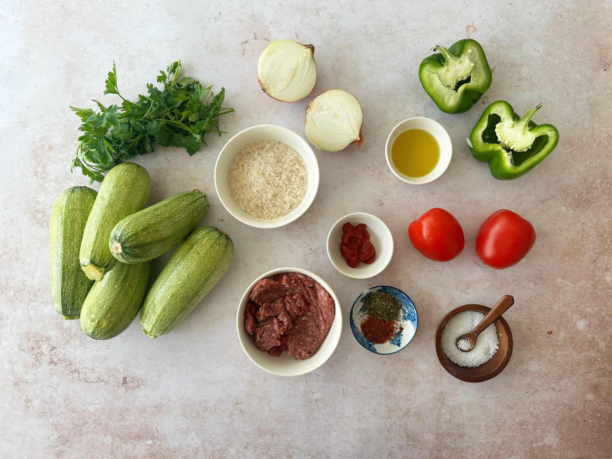 Kabak Dolmasi Ingredients ingredients for Kabak Dolmasi including spices, peppers, jasmine rice, zucchini, parsley, tomatoes, and olive oil