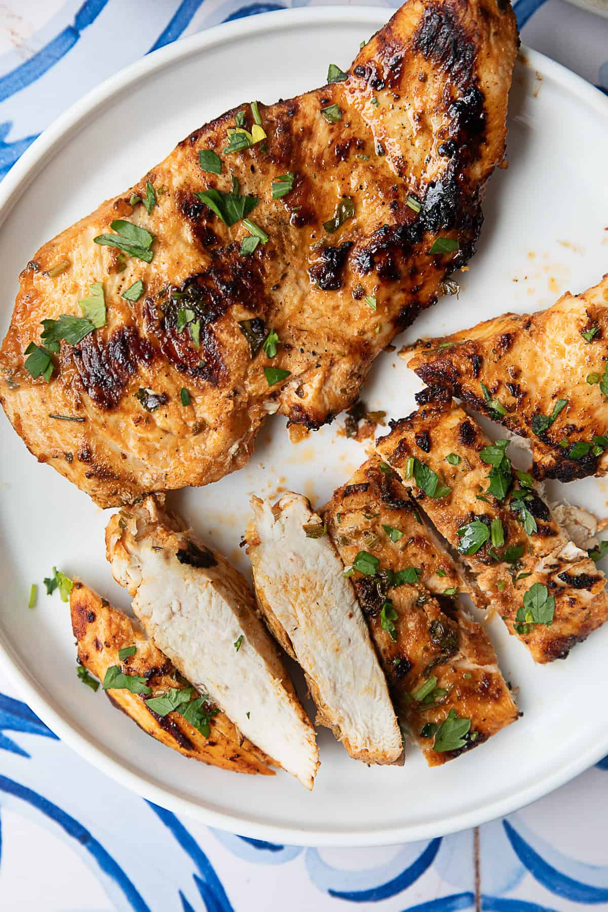 Juicy Middle Eastern-Inspired Grilled Chicken Breast Recipe Middle Eastern-inspired grilled chicken breast with on piece sliced and served on a white platter