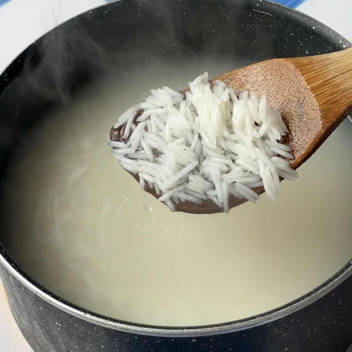 boiled rice in a pot and a wooden spoon with some boiled rice grains