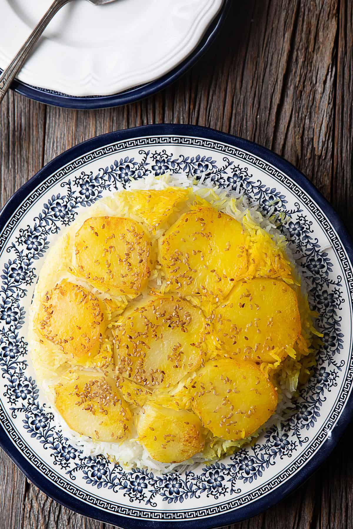 Golden potato slices on top of fragrant saffron rice, served in a traditional Iranian pot, showcasing the rich culinary heritage of Persian cuisine.