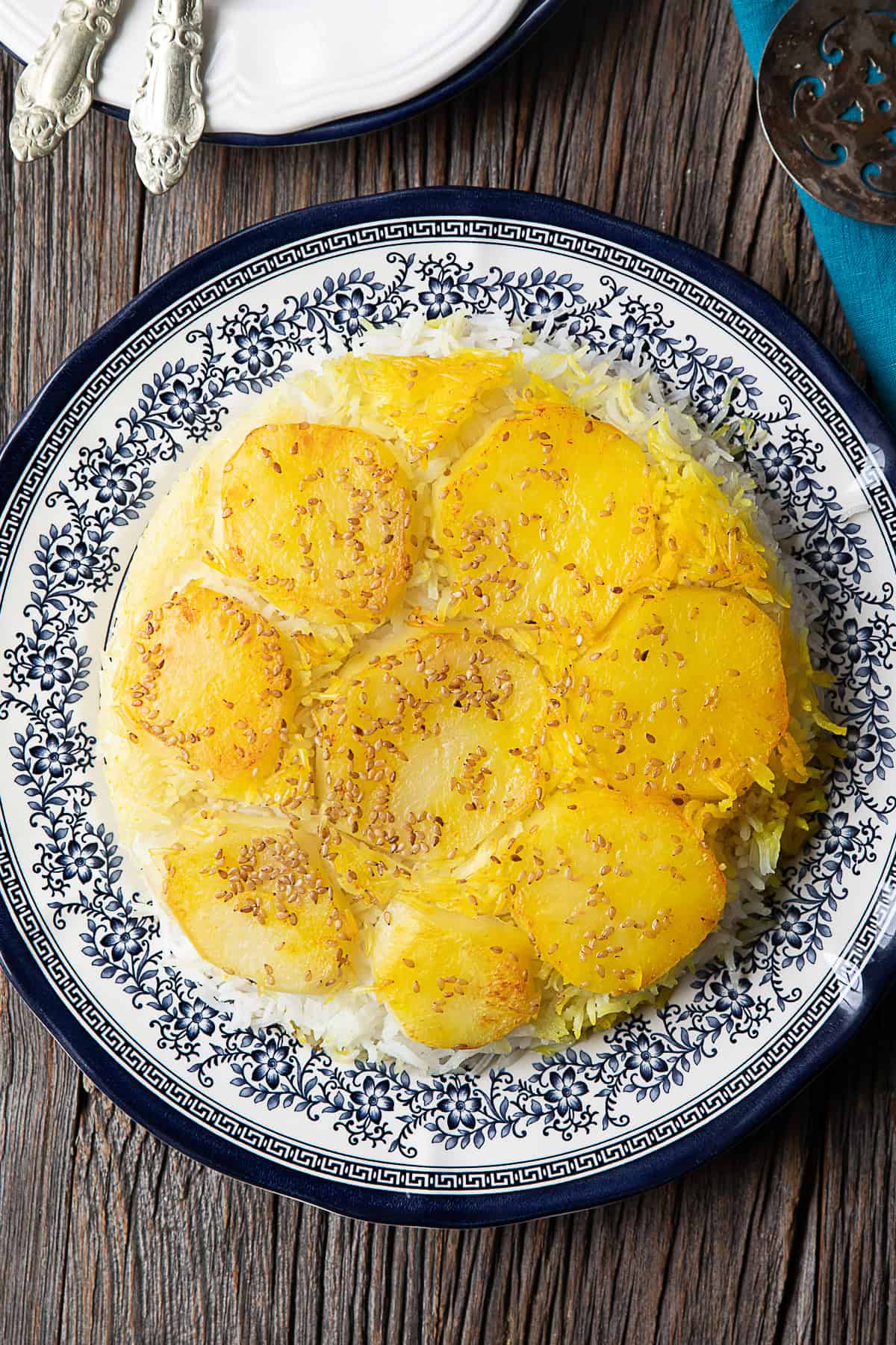 Persian potato tahdig: A golden crispy layer of thinly sliced potatoes atop fluffy saffron-infused rice, served in a traditional Persian pot.