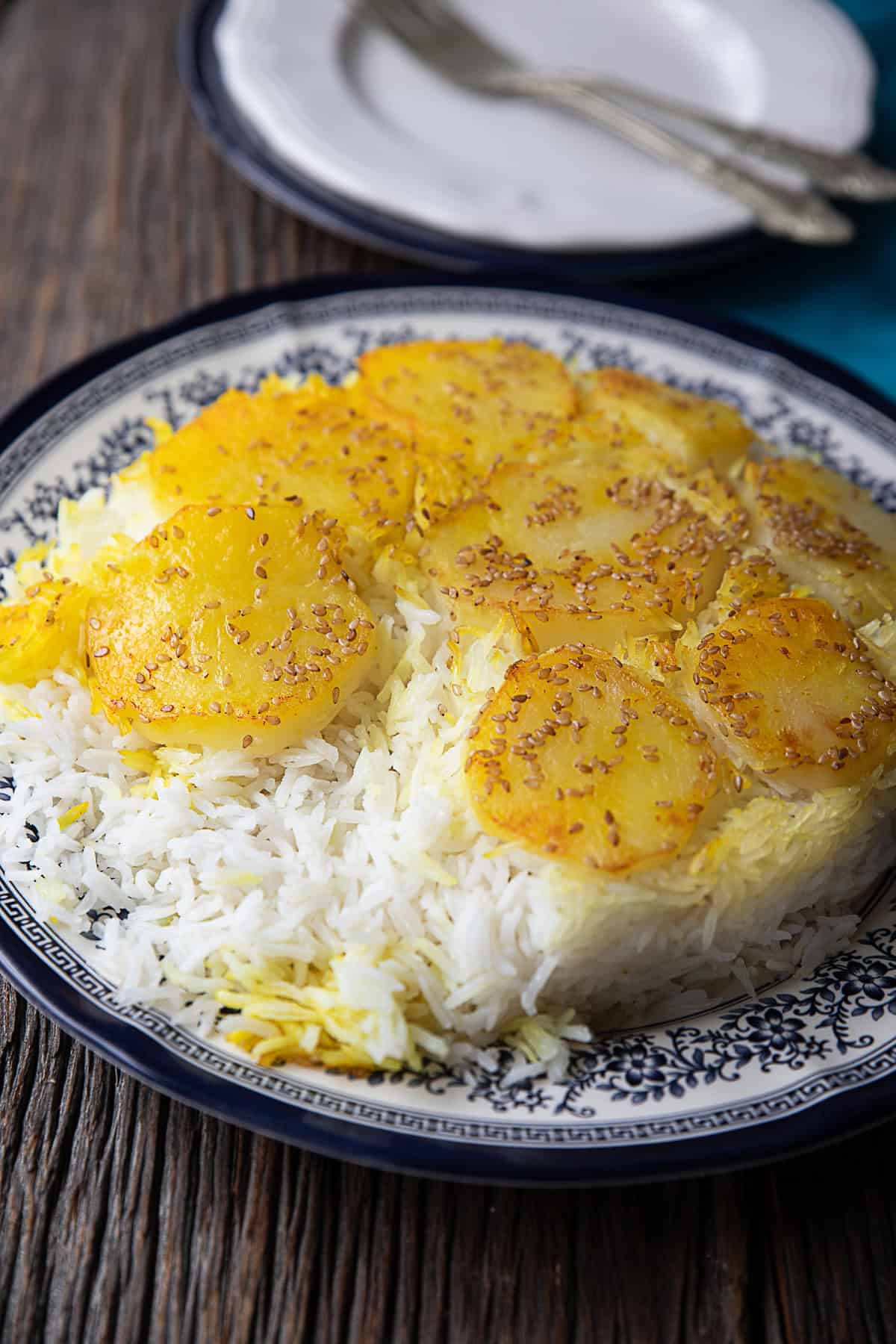 A delicious serving of Persian potato tahdig: Crispy golden potato slices layered over aromatic saffron rice, showcasing the traditional Iranian culinary artistry.