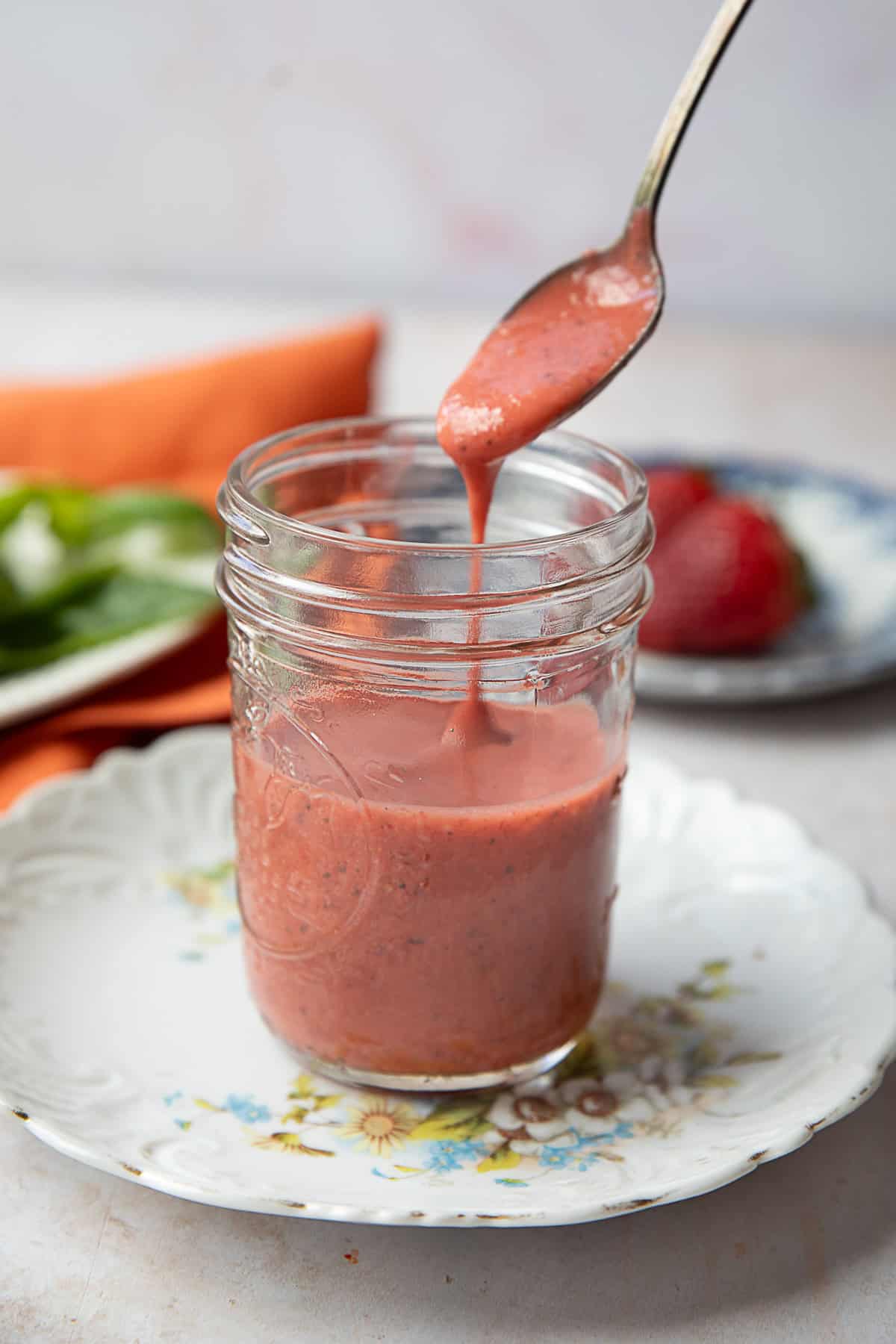 Creamy Strawberry Vinaigrette strawberry vinaigrette served in a transparent jar with a spoon drizzling some