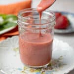 strawberry vinaigrette served in a transparent jar with a spoon drizzling some