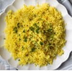 Mediterranean yellow rice cooked to perfection and served on a white platter with garnish