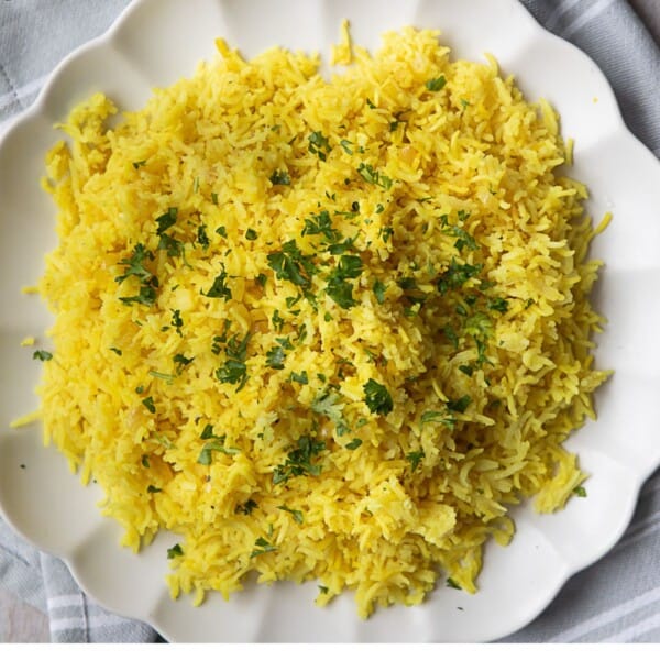 Mediterranean yellow rice cooked to perfection and served on a white platter with garnish