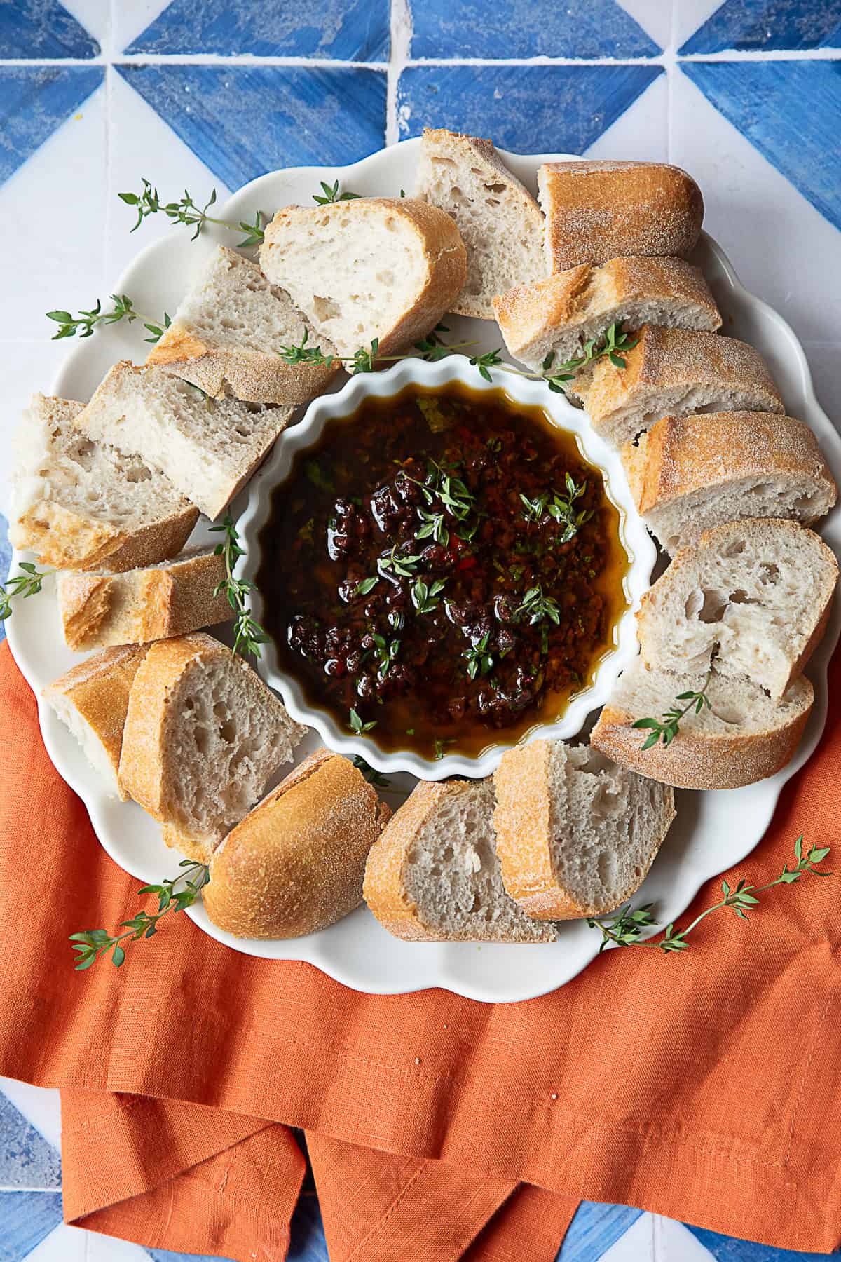 Viral Olive Oil Bread Dip olive oil bread dip in a small white bowl placed on a white serving platter with crusty bread