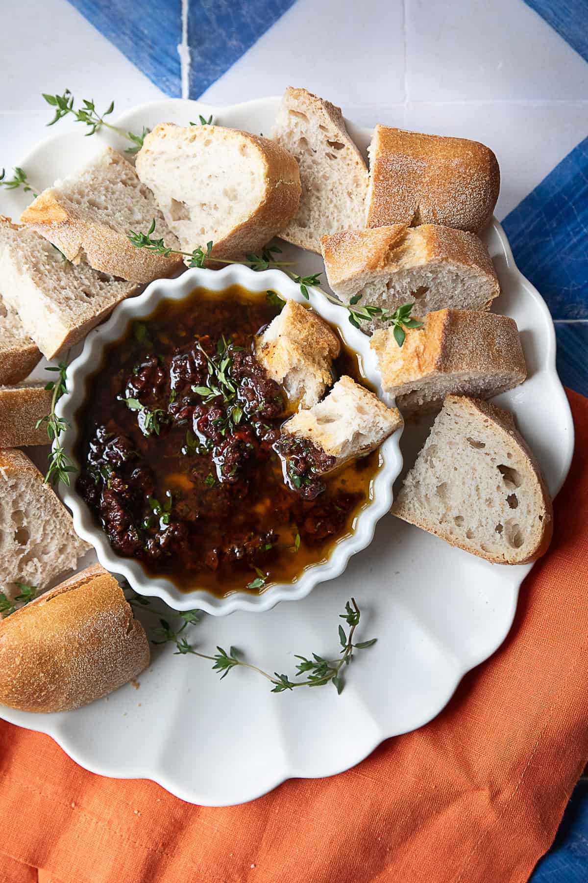 Olive Oil Bread Dip olive oil bread dip in a small white bowl placed on a white serving platter with crusty bread