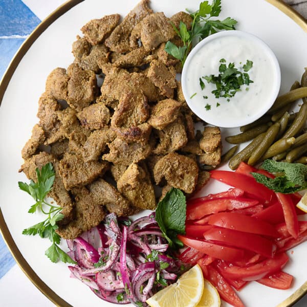 seared lamb shawarma on a plate with fixings