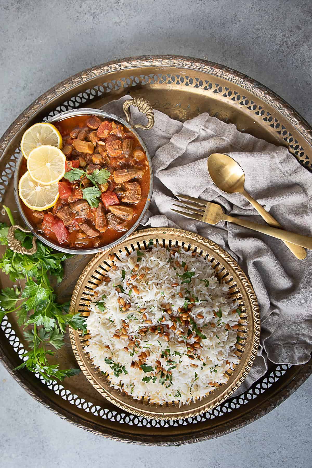 Comforting Bamya Recipe a bowl of bamya okra stew served hot topped with lemon wedges alongside a plate of vermicelli rice topped with sautéed pine nuts