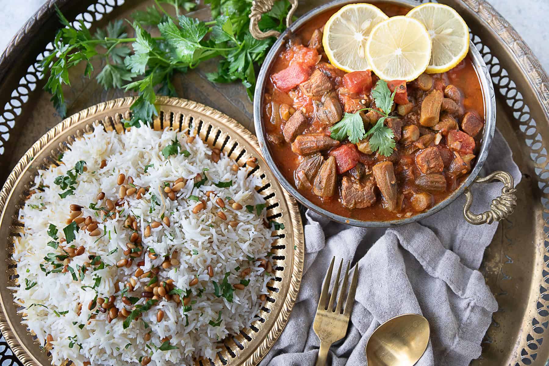 Bamya - Middle Eastern Okra Stew A bowl of bamya stew served hot with a plate of vermicelli rice topped with sautéed pine nuts