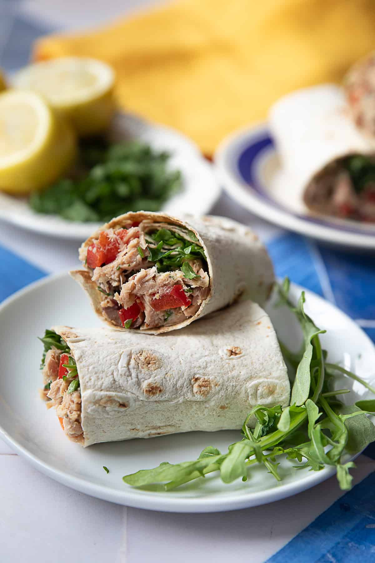 a close up view of two slices of Middle Eastern tuna wraps served alongside of arugula leaves
