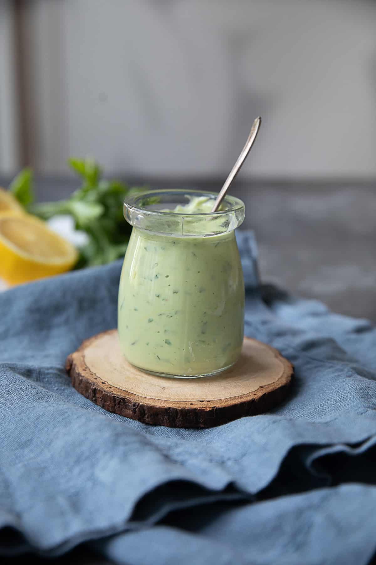 a jar of greek avocado sauce placed on a circular wooden support