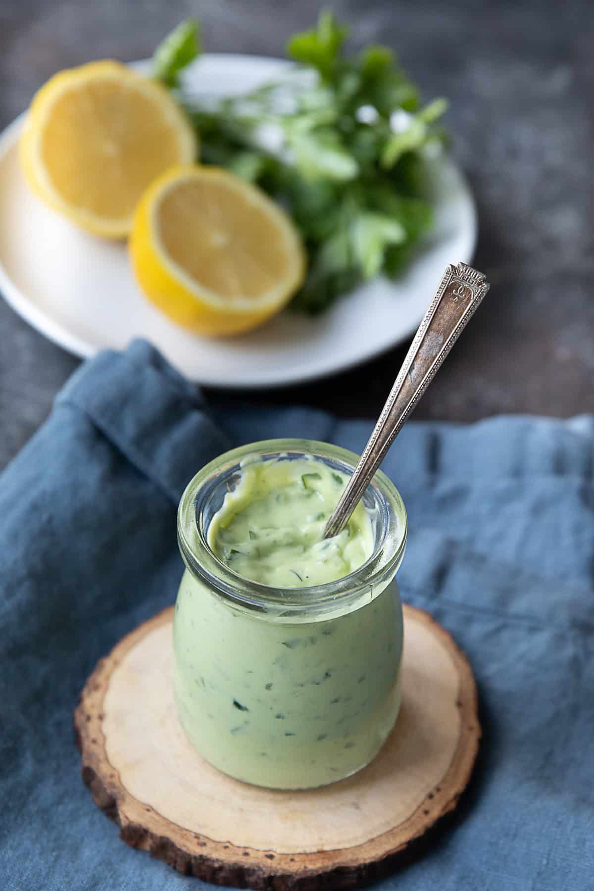 a top view of a jar of avocado sauce placed on a circular wooden support