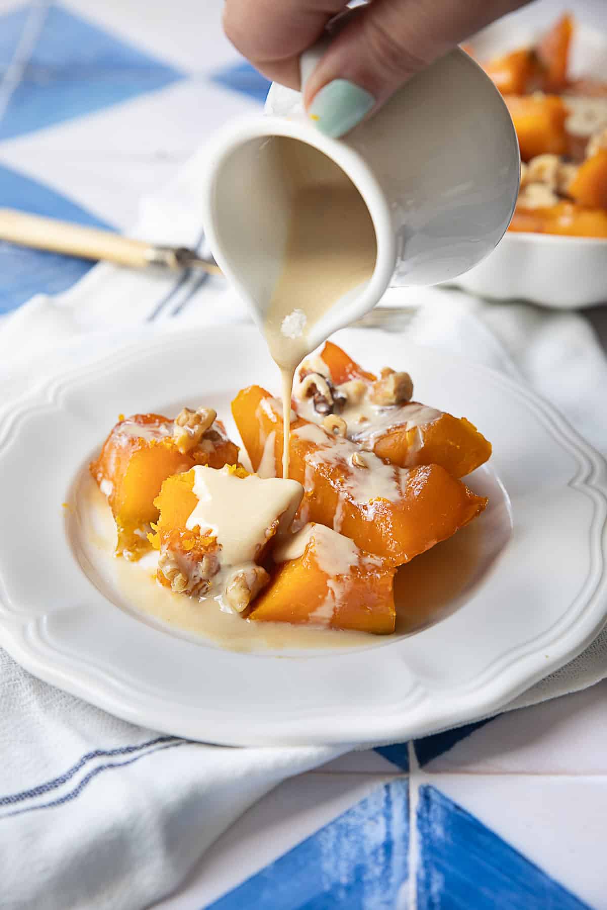 Kabak Tatlısı A plate of delicate pumpkin pieces drizzled with tahini sauce and topped with chopped walnuts.