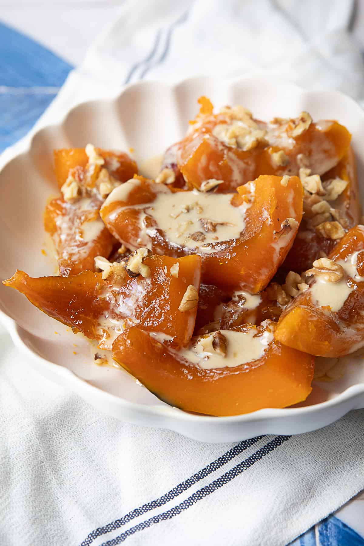 Kabak Tatlisi Tarifi A plate of Turkish Kabak Tatlisi Dessert topped with tahini and sprinkled with crushed walnuts.